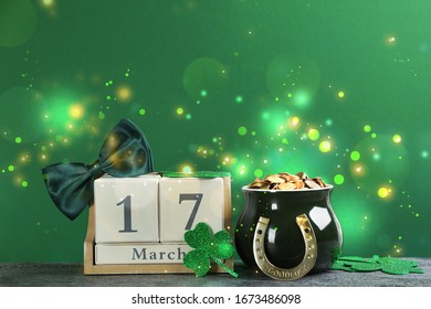 Composition with pot of gold coins and wooden block calendar on grey stone table against green background. St. Patrick's Day celebration - Powered by Shutterstock