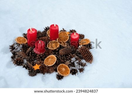 composition with red burning candles, cones, dry orange slices in snow, winter nature background. Christmas, New Year, Yule Holidays. witchcraft, magic, esoteric spiritual ritual for winter solstice