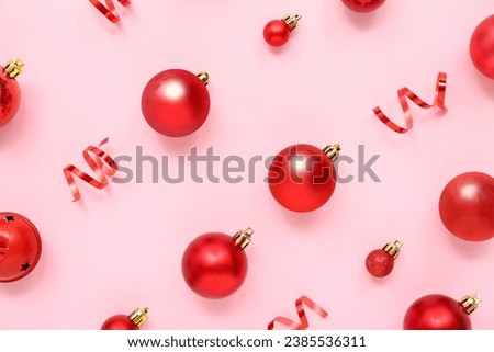 Composition with red Christmas balls and ribbons on pink background