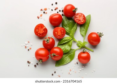 Composition with ripe cherry tomatoes, basil leaves, sea salt and peppercorn on light background