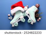 Composition with roller skates, Santa hat and Christmas decorations on blue background