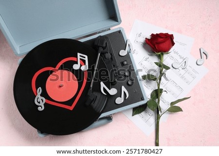 Composition with rose flower, record player, sheet notes and decorative music notes on pink grunge background