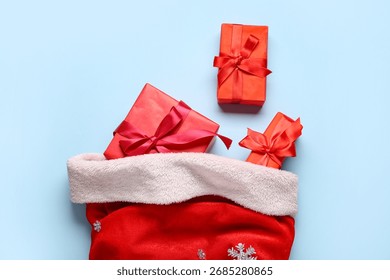 Composition with Santa bag and gift boxes on blue background, closeup