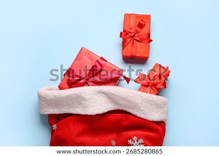 Composition with Santa bag and gift boxes on blue background, closeup