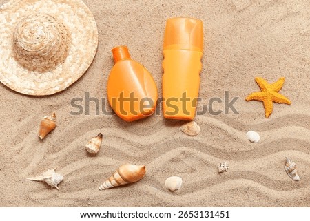 Composition with seashells, starfish, bottles of sunscreen cream and decorative hat on sand as background