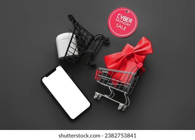 Composition with shopping carts, gadgets and gift box on black background. Cyber Monday sale - Powered by Shutterstock