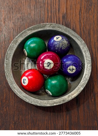A composition of six pool balls in a copper dish on a stall at the antique market.