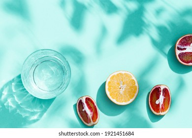 Composition with slices grapefruit, red orange, lemon and drink glass on turquoise colored background. Summer time flat lay with daylight. - Shutterstock ID 1921451684