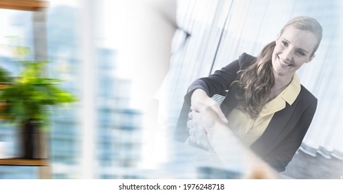 Composition of smiling businesswoman and colleague shaking hands in office with motion blur. global business, partnership and success concept digitally generated image.