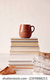 Composition with a stack of books, hot beverage in the mug and warm blanket. Cozy reading scene for cold weather with cup of coffee