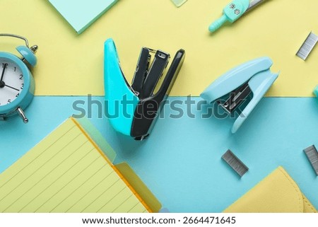 Composition with staplers and different school stationery on color background