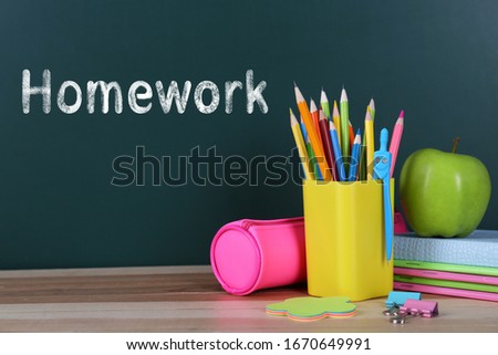 Composition with stationery and apple on table near chalkboard. Doing homework