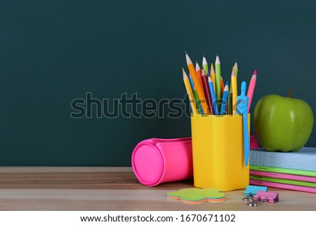 Composition with stationery and apple on table near chalkboard, space for text. Doing homework