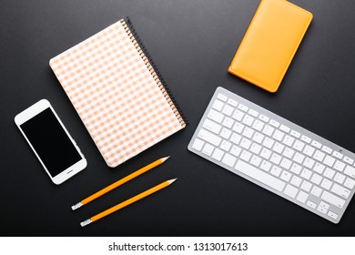 Composition with stationery, computer keyboard and mobile phone on dark background