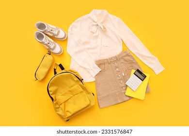 Composition with stylish school uniform, backpack, sneakers and stationery on orange background