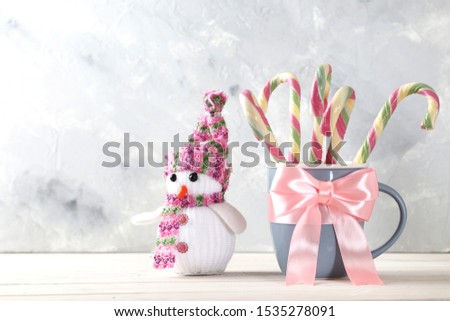 Composition with sweet candy cane, bow,  in a cup on color background 
