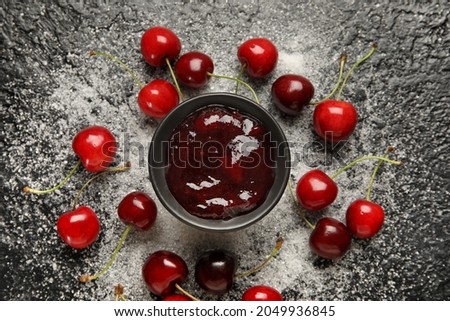 Composition with sweet cherry jam and sugar on dark background