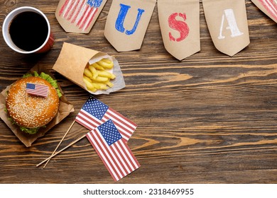 Composition with tasty burger, french fries, cola and paper decor on wooden background. Memorial Day celebration