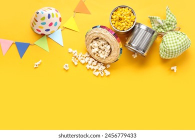 Composition with tasty popcorn, corn, bundle bag and decor for Festa Junina celebration on yellow background