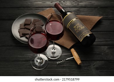 Composición con un delicioso vino tinto y chocolate sobre una mesa de madera negra