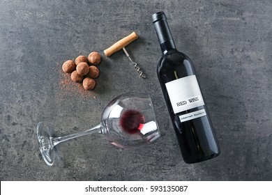 Composition of tasty truffles, wine bottle and glass on grey background