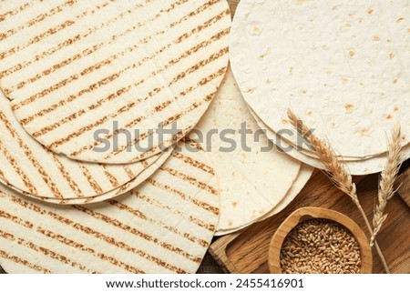 Composition with thin lavash and bowl of wheat grains on wooden background