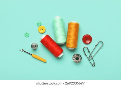 Composition with thread spools, thimble and buttons on mint background