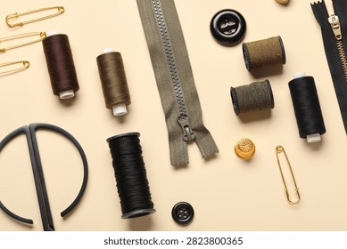 Composition with thread spools, zippers and buttons on beige background, closeup