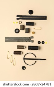 Composition with thread spools, zippers, pins and buttons on beige background