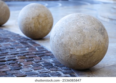 The composition of three marble spheres is located on a granite floor, the structure and texture of the first sphere is clearly visible.