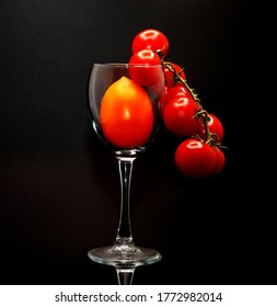 Composition of tomatoes of different sizes and colors in a wine glass. Natural product. Natural color. Close-up.