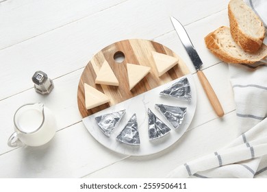 Composition with triangles of tasty processed cheese, bread, milk and knife on light wooden background