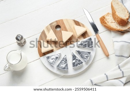 Composition with triangles of tasty processed cheese, bread, milk and knife on light wooden background