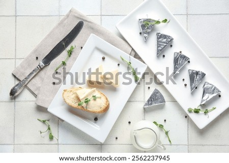 Composition with triangles of tasty processed cheese, bread, micro green and spices on light tile background