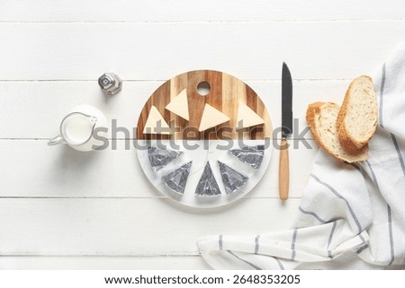 Composition with triangles of tasty processed cheese, bread, milk and knife on light wooden background