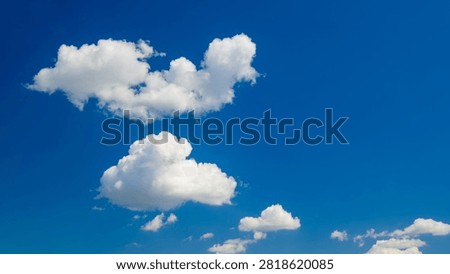 composition of two volumetric white cumulus clouds arranged vertically against blue sky background