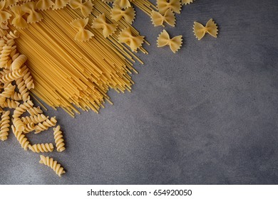 Composition of uncooked italian pasta. Spaghetti, farfalle, fusilli on dark wooden background. Raw pasta background.  - Powered by Shutterstock