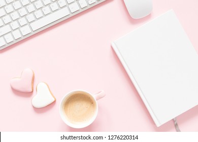 Composition Valentine's Day. Female desktop сomputer keyboard, сup of coffee and ginger cookie in shape heart on pastel pink background. Valentine day concept, design.  