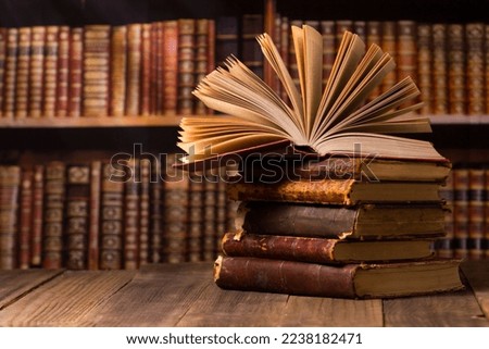 Composition with vintage old hardback books, diary, fanned pages on wooden deck table and red background. Books stacking. Back to school. Copy Space. Education background.	