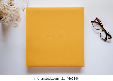 Composition With A Wedding Or Family Photo Album, Made Of Natural Yellow Linen Fabric On A White Background. Flat Lay, Top View Still Life.