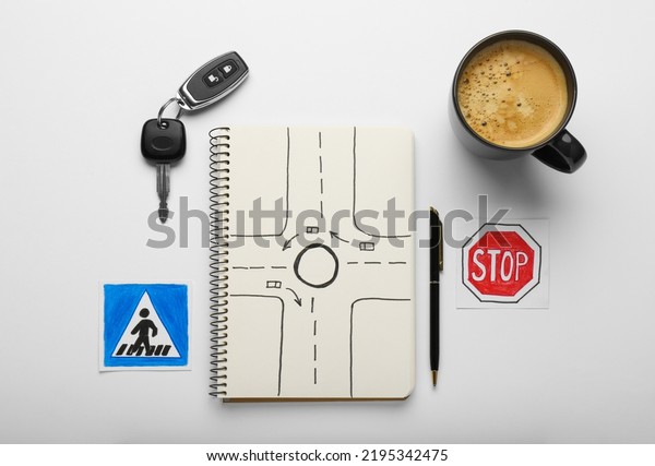 Composition with workbook for\
driving lessons on white background, top view. Passing license\
exam