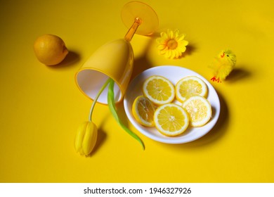 Composition Of Yellow Tulip, Lemon Fruits, Flower And Fake Chicken On Yellow Background