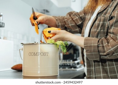 Compost the kitchen waste, recycling at home. Compost bin with vegetables cutted leftovers on the kitchen table with blurred woman cooking meal. Environmentally responsible, ecology. Selective focus - Powered by Shutterstock