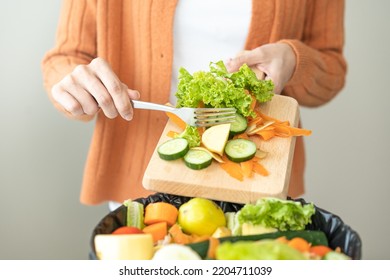 Compost from leftover food, asian young housekeeper woman hand holding cutting board use fork scraping waste, rotten vegetable throwing away into garbage, trash or bin. Environmentally responsible. - Powered by Shutterstock