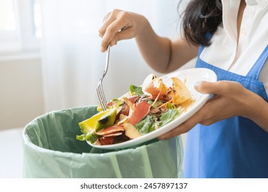 Compost from leftover food asian young housekeeper woman, female hand holding salad bowl use fork scraping waste, rotten vegetable throwing away into garbage, trash or bin. Environmentally responsible - Powered by Shutterstock