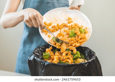 Compost from leftover food asian young housekeeper woman, girl hand holding macaroni plate use fork throw away food scraps, rotten vegetable into trash. Environmentally responsible, food waste concept - Powered by Shutterstock