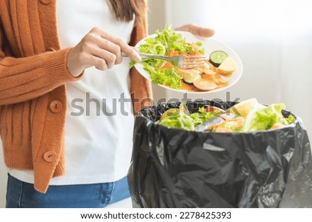 Compost from leftover food, asian young housekeeper woman hand holding cutting board use fork scraping waste, rotten vegetable throwing away into garbage, trash or bin. Environmentally responsible. [[stock_photo]] © 