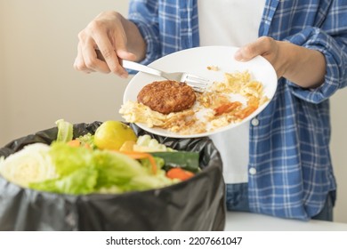 Compost from leftover food, refuse asian young housekeeper woman, girl hand using fork scraping waste from dish, throwing away putting into garbage, trash or bin.Environmentally responsible, ecology.
