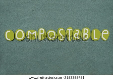 Compostable of organic matter, especially kitchen waste, able to be made into compost, creative word composed with green colored stone letters over green sand