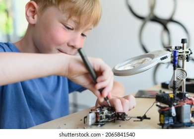 Comprehensive Development Of The Child. Hobbies For Advanced Smart Kids. Young Inventor Boy Carefully Assembling Robotic Toy With Screwdriver.